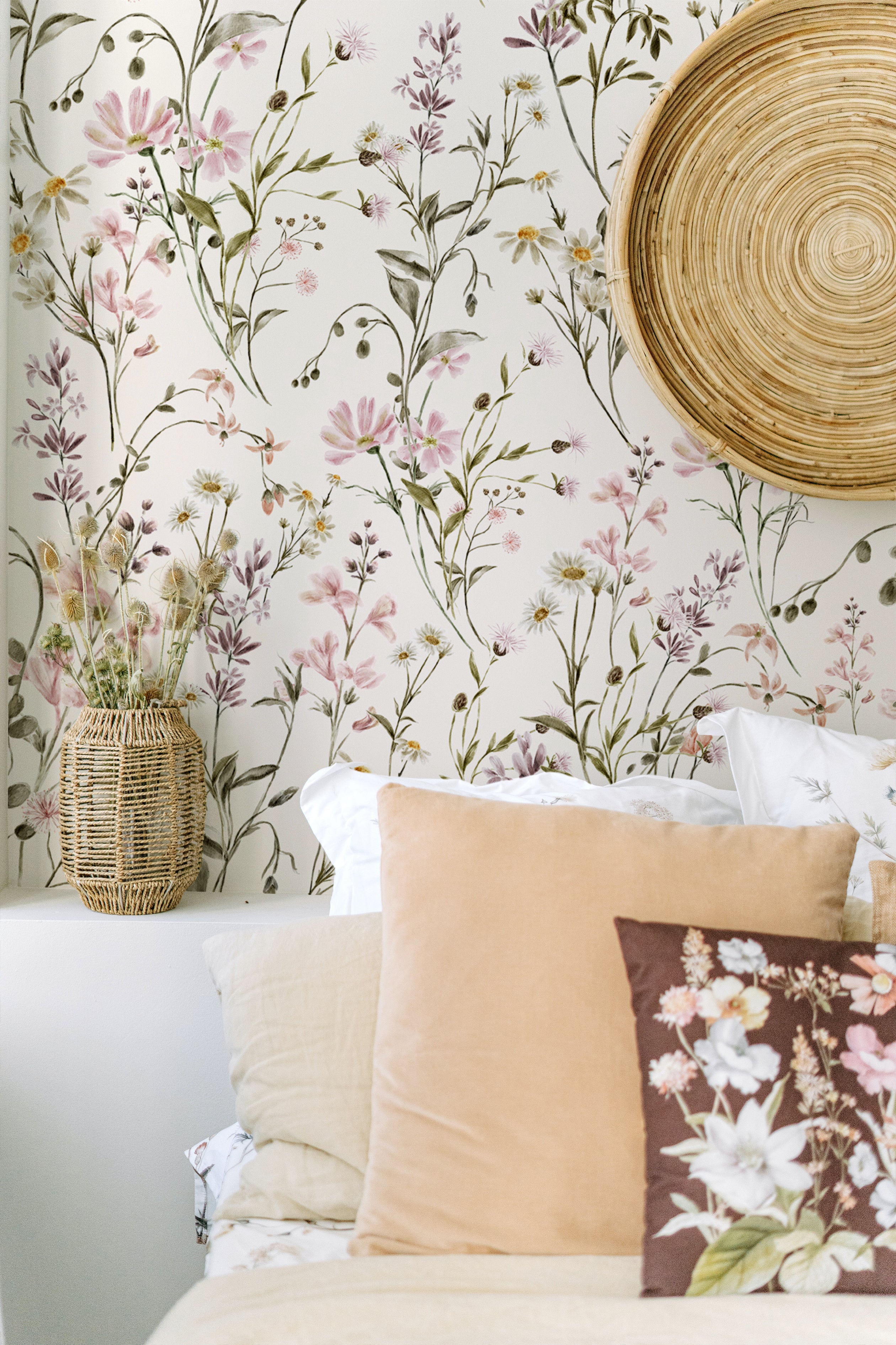A cozy bedroom corner is brightened by the "WildFloral Wallpaper - 75"," which covers the wall with a beautiful pattern of watercolor wildflowers. The natural theme is complemented by a wicker basket vase, woven wall art, and soft-hued pillows that echo the colors of the florals.