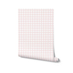 A roll of Gingham Wallpaper displaying its soft pink and white checkered pattern, ready to be applied to walls for a charming and cozy look.