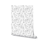 A roll of elegant monochrome wallpaper unrolled to display the full pattern. The design features a delicate black and white floral pattern with various flowers and leaves. The intricate and sophisticated look makes it ideal for adding a touch of elegance and style to any room.