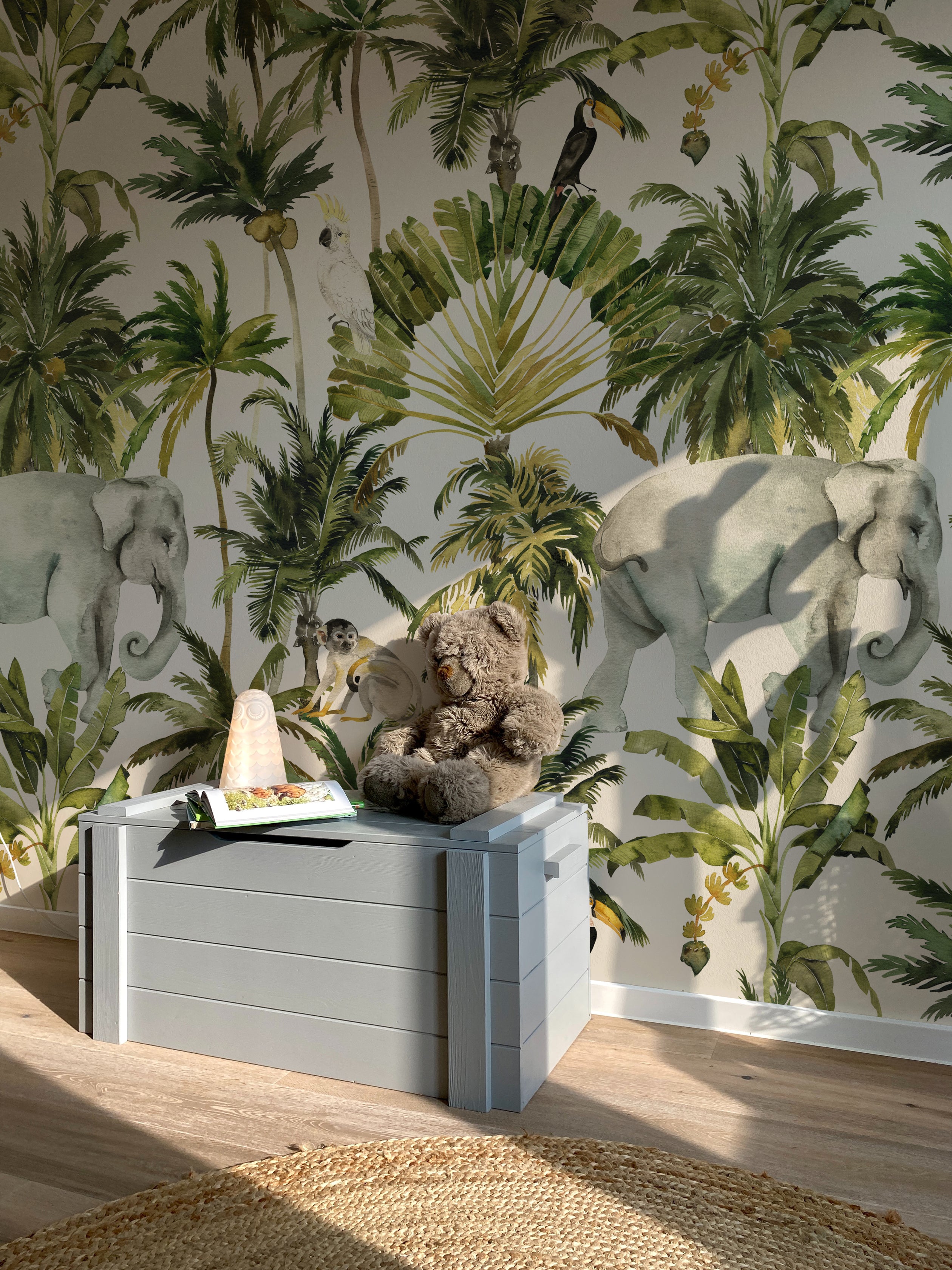 Interior shot showing a room adorned with Elephant and Palm Wallpaper - 75", which depicts a rich tropical scene including an elephant, various palms, and a cockatoo, enhancing the room with a sense of adventure and natural beauty.