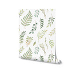 A roll of Green Foliage Wallpaper displaying a beautiful pattern of hand-drawn green leaves and branches on a white background, perfect for adding a touch of nature to any room.