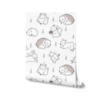 Rolled sample of Winter Friends Wallpaper, showcasing a sweet and serene pattern of friendly woodland animals and pine trees on a white background, perfect for creating a warm and inviting atmosphere in any child's room