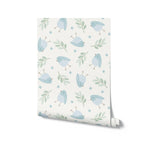 A roll of Baby Blue Bird Wallpaper unrolled to show a repetitive pattern of cute blue birds and green foliage on a white background, ideal for adding a touch of whimsy and calm to children's rooms or play areas