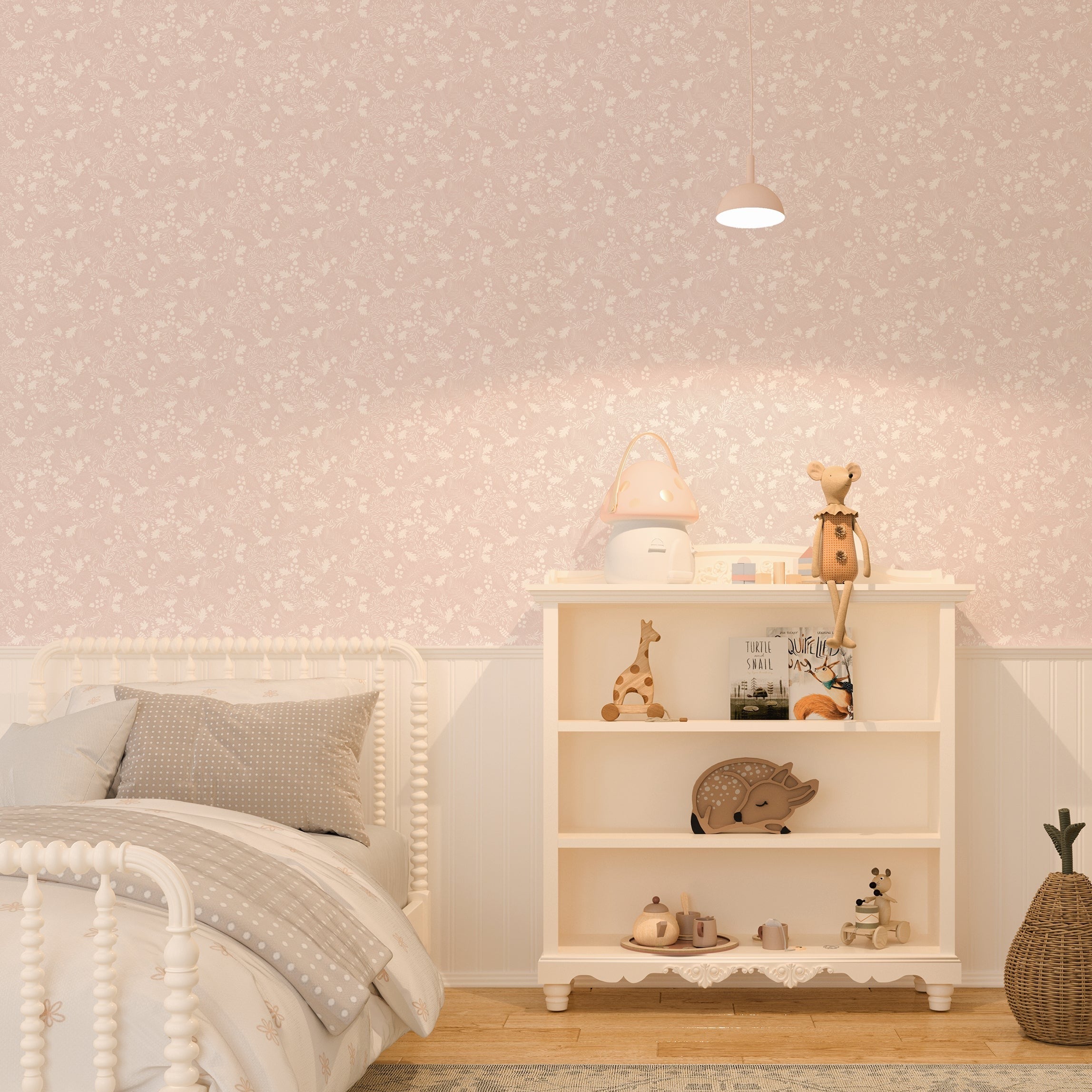 A cozy nursery featuring Whispering Woodland wallpaper with its white leaf patterns on a soft pink background. The room is decorated with a white bed, a shelf filled with toys, and a small pendant lamp illuminating the space.