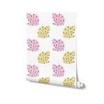 A roll of playful cat-themed wallpaper illustrated with rows of pink and yellow cats, each embellished with black spots and lines. This wallpaper roll showcases a whimsical and cheerful design, perfect for adding a touch of fun to any room