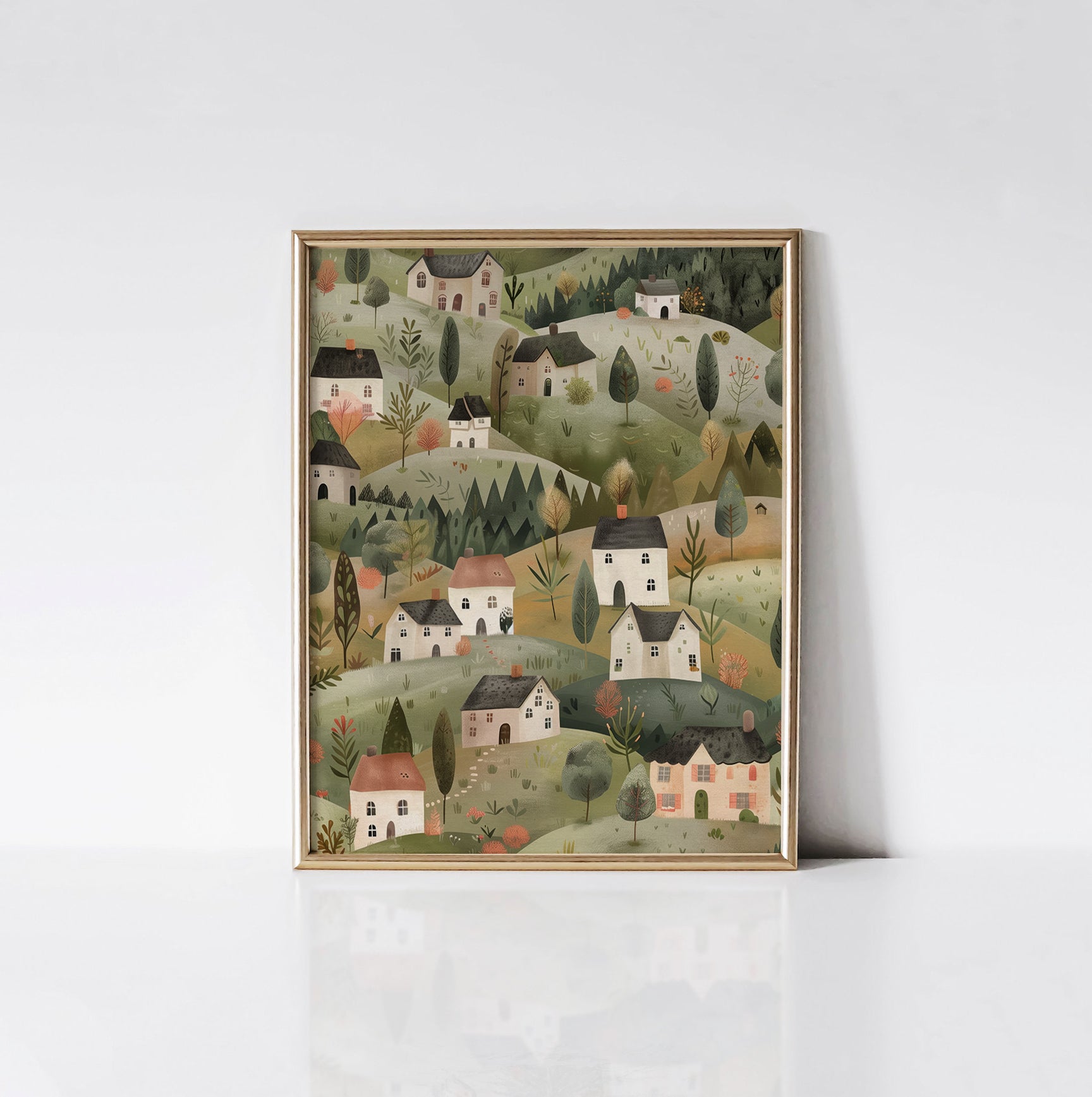 The "Enchanted Village" art print displayed in a gold frame, featuring an idyllic countryside landscape with picturesque cottages, vibrant trees, and gentle hills.