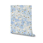A roll of Blue Fleur Wallpaper - 25 showcasing the detailed floral pattern with blue cosmos flowers and yellow centers on a pale blue background. The image captures the lively yet soothing design, ready to transform any room with its bright and cheerful aesthetic.