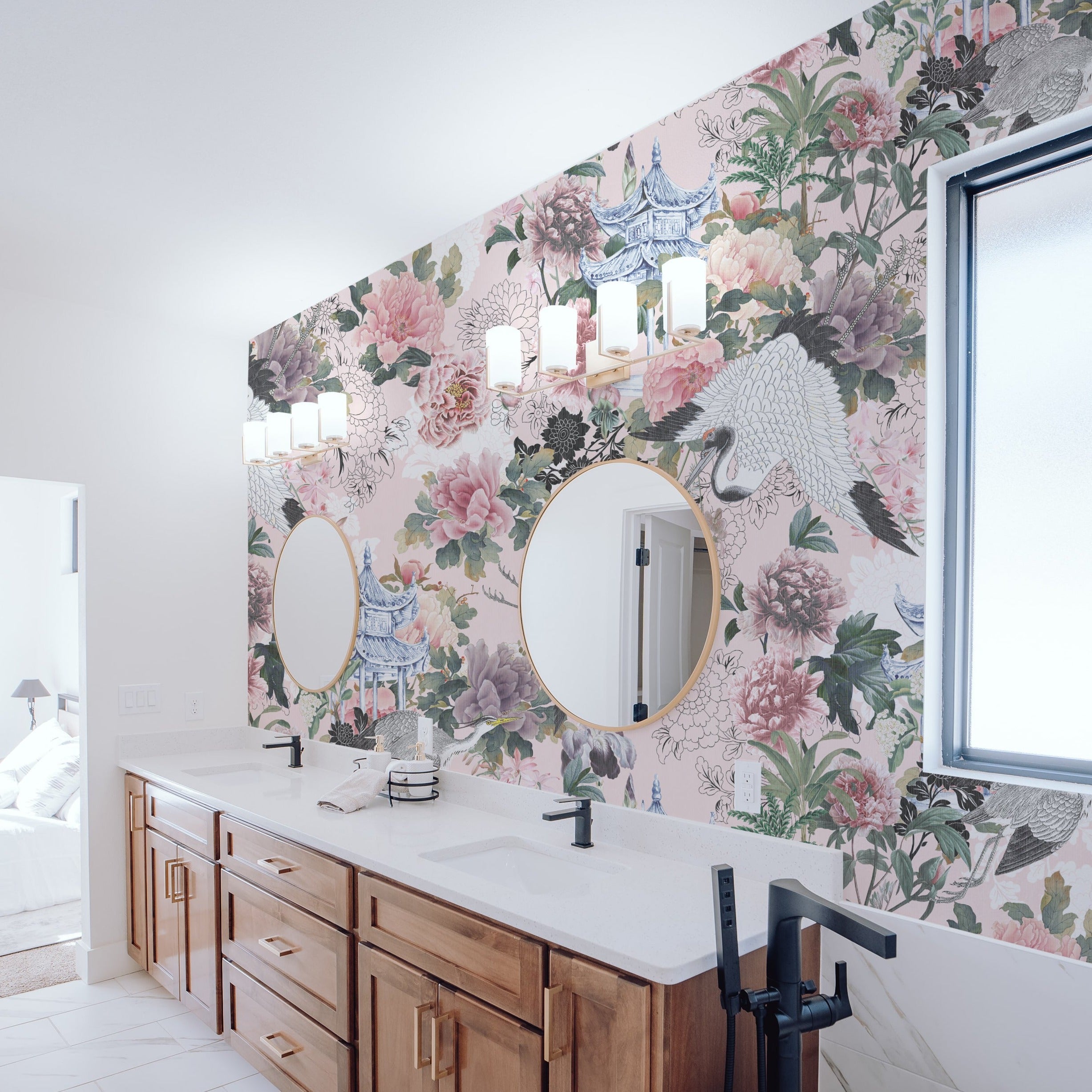 Modern bathroom decorated with Pink Kyoto Dreams Wallpaper, highlighting its lush floral and bird motifs with pink and gray accents. The design complements the sleek white countertops, round mirrors, and wooden cabinetry, enhancing the space with a touch of oriental elegance