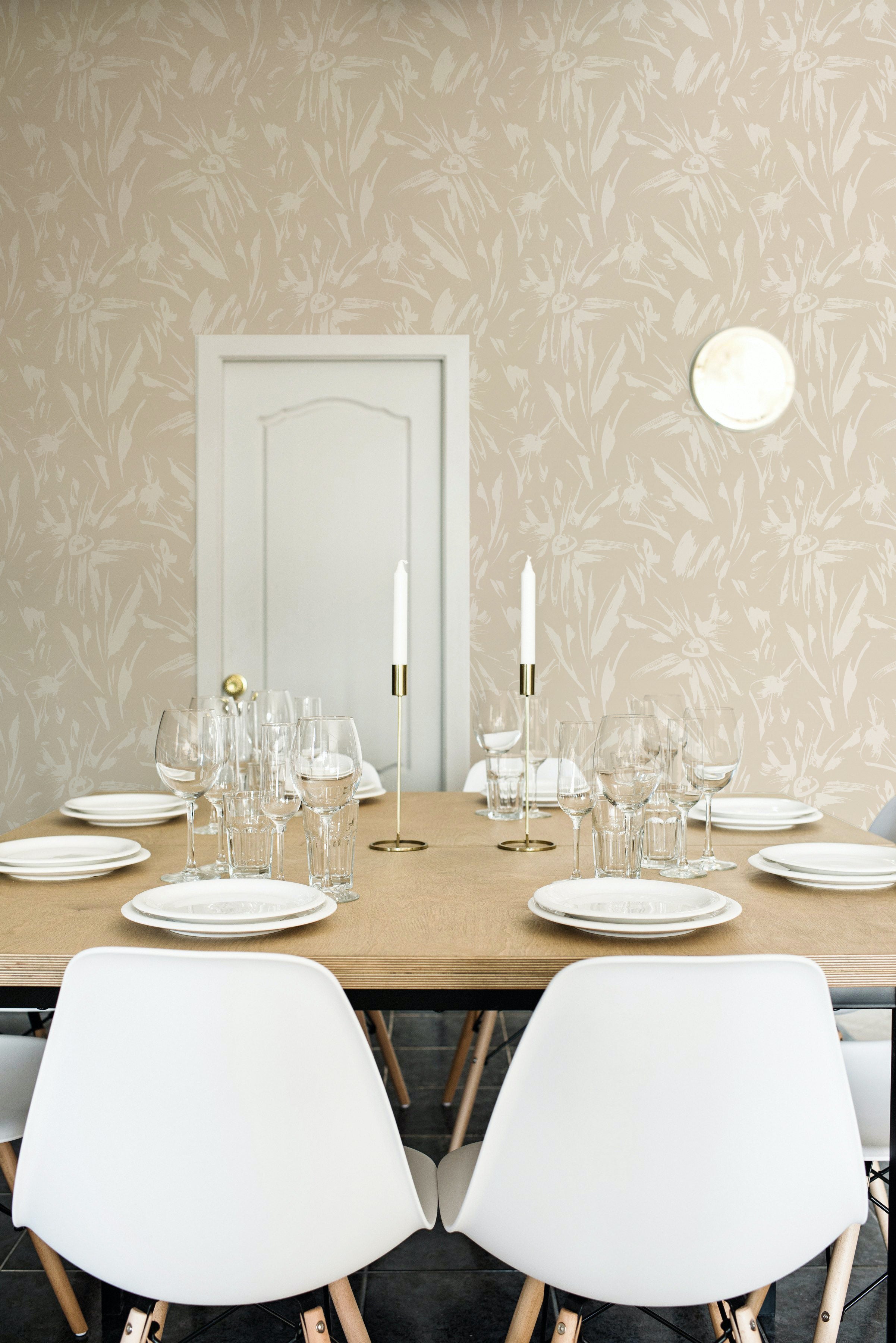 A modern dining room featuring the Ecru Floral Sketch Wallpaper - 25". The wallpaper, with its subtle beige floral sketches on an ecru background, adds an understated elegance to the space, complemented by the simple white chairs, wooden table, and minimalist decor.