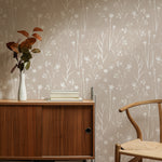 Modern home office accented with Subtle Meadow Floral Wallpaper, depicting soft white floral and stem patterns on a taupe background, beside a wooden desk and chair.