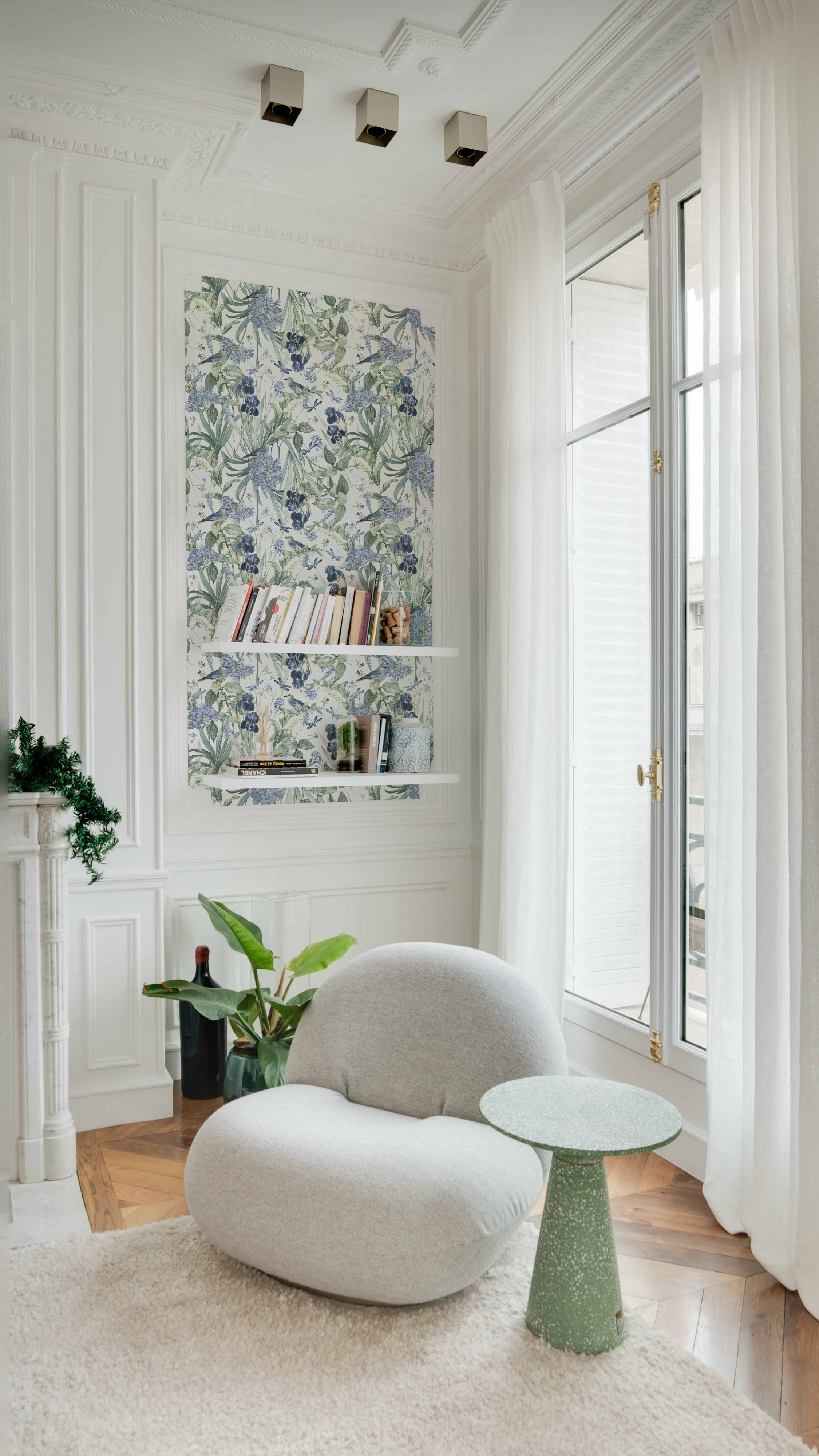 An elegant living space with Mint Floral Wallpaper used as a feature wall behind white floating shelves. The wallpaper adds a refreshing botanical vibe with its detailed depiction of birds and flowers, enhancing the light and airy feel of the room.