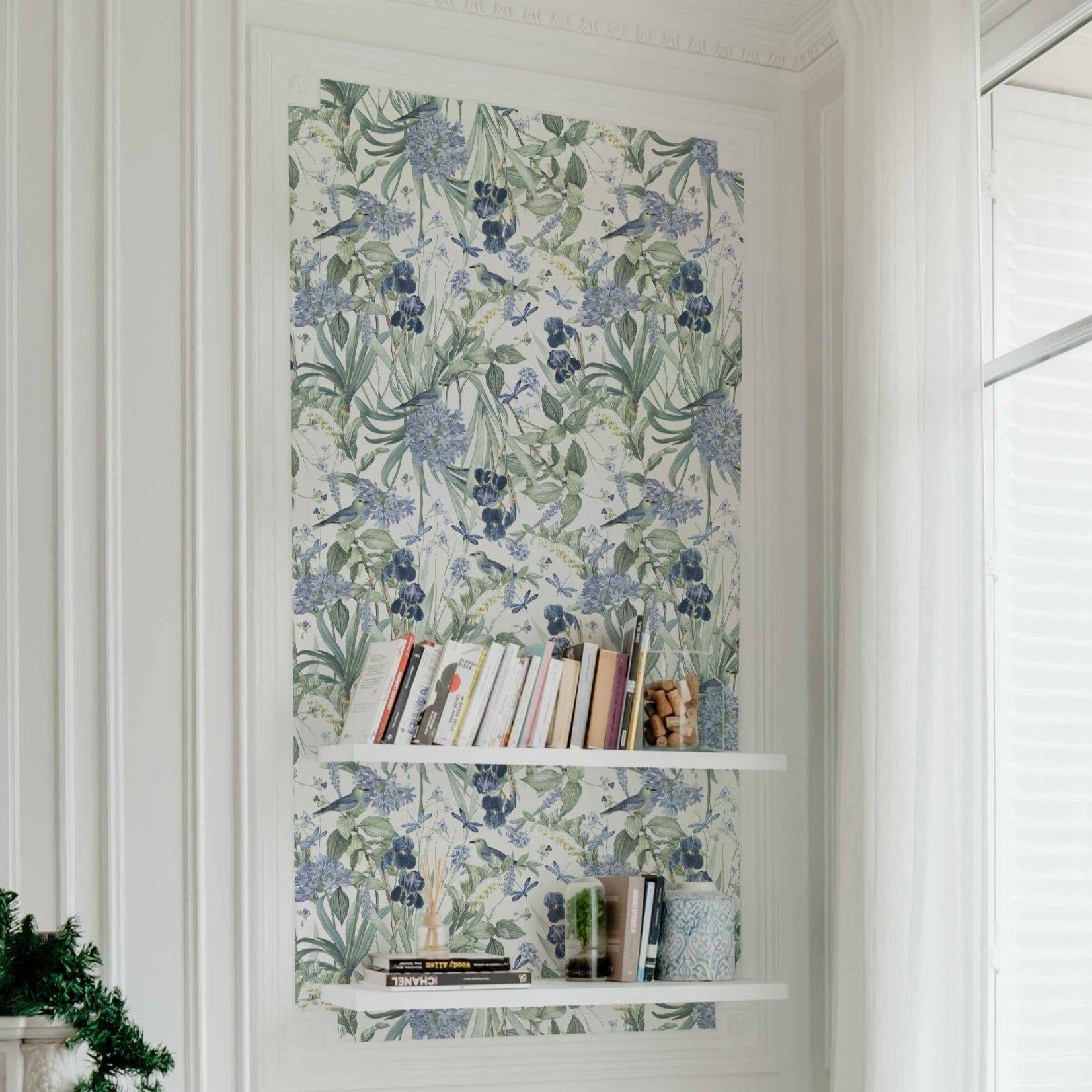 A close-up of the Mint Floral Wallpaper on a wall, offering a detailed view of the wallpaper's intricate design. The pattern includes various shades of blue flowers and green leaves, complemented by small birds and dragonflies, creating a tranquil natural scene.
