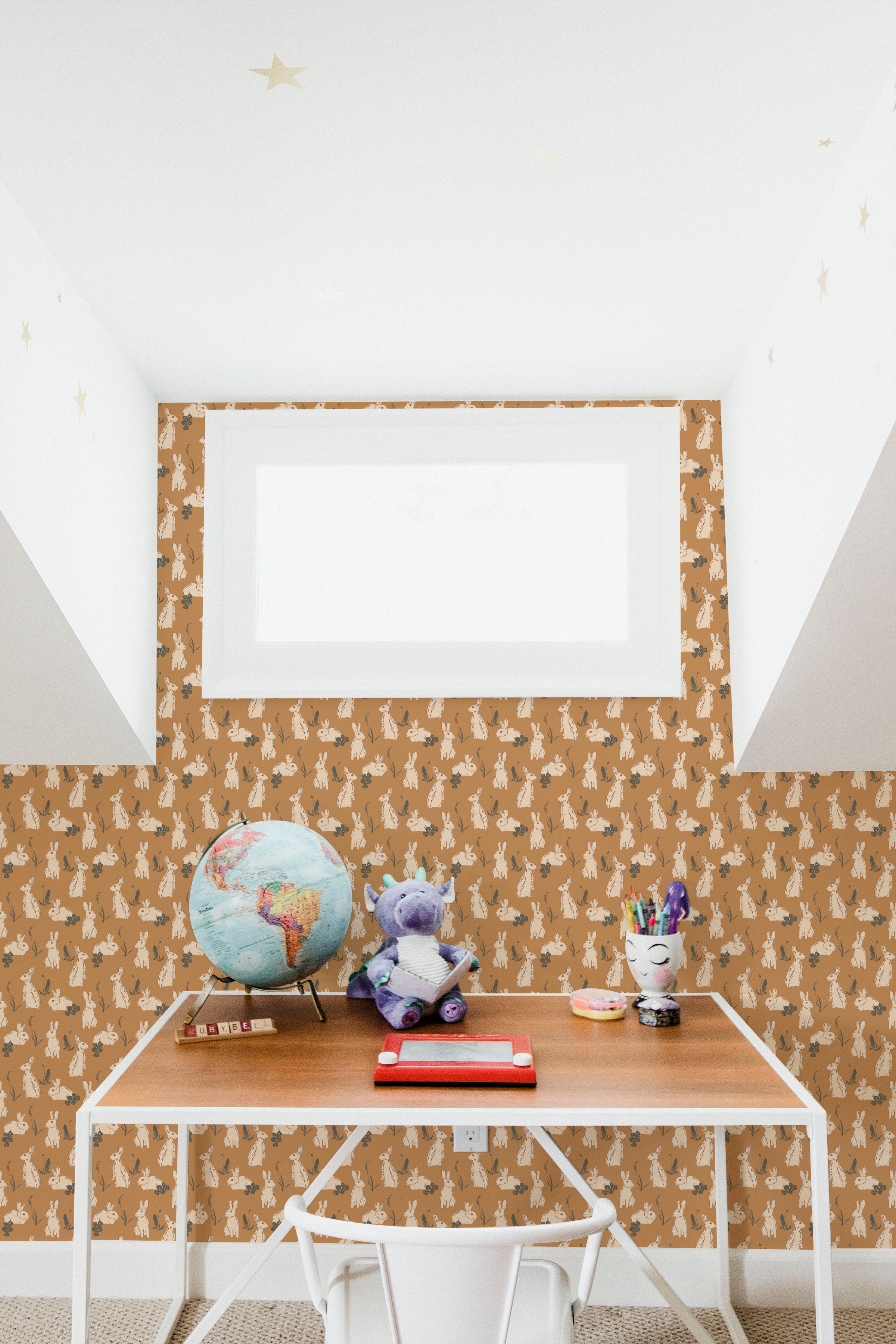 A playful children's study space with a wall adorned with rabbit-themed wallpaper in soft beige, topped with whimsical golden stars on the ceiling, enhancing the room's imaginative charm.