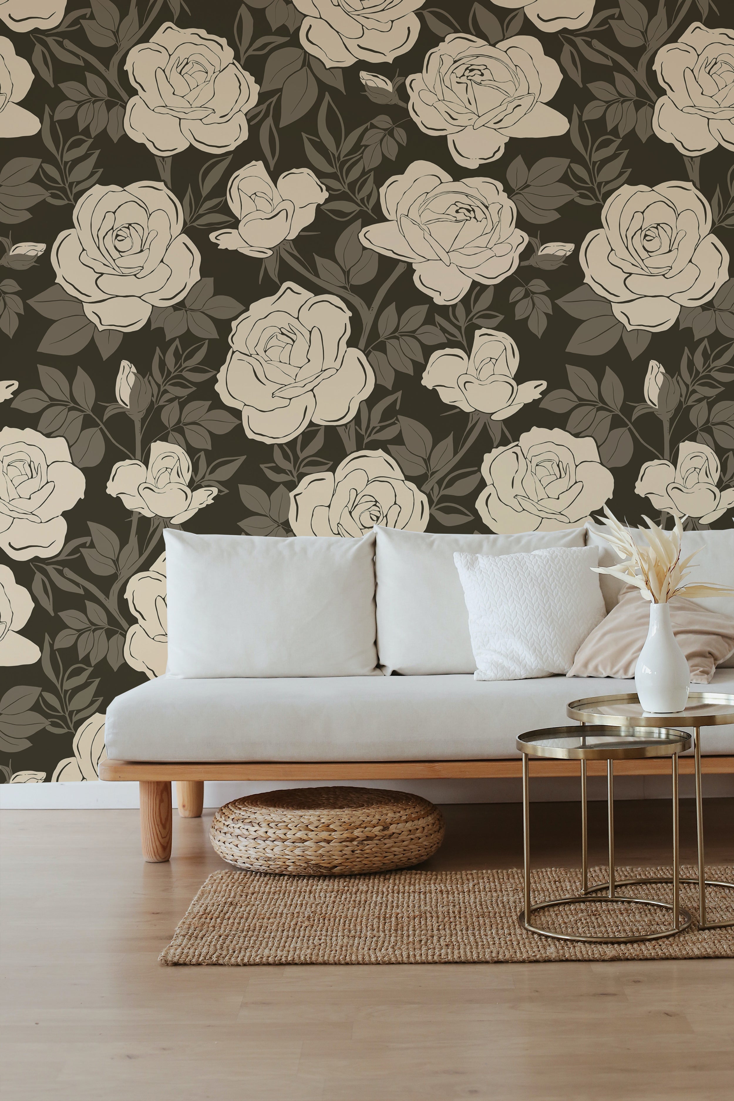 Chic, minimalist lounge area adorned with a floral wallpaper showcasing large cream roses on a dark background. The setting includes a light gray sofa, a natural wood coffee table, and a woven floor pouf, emphasizing a clean and tranquil space