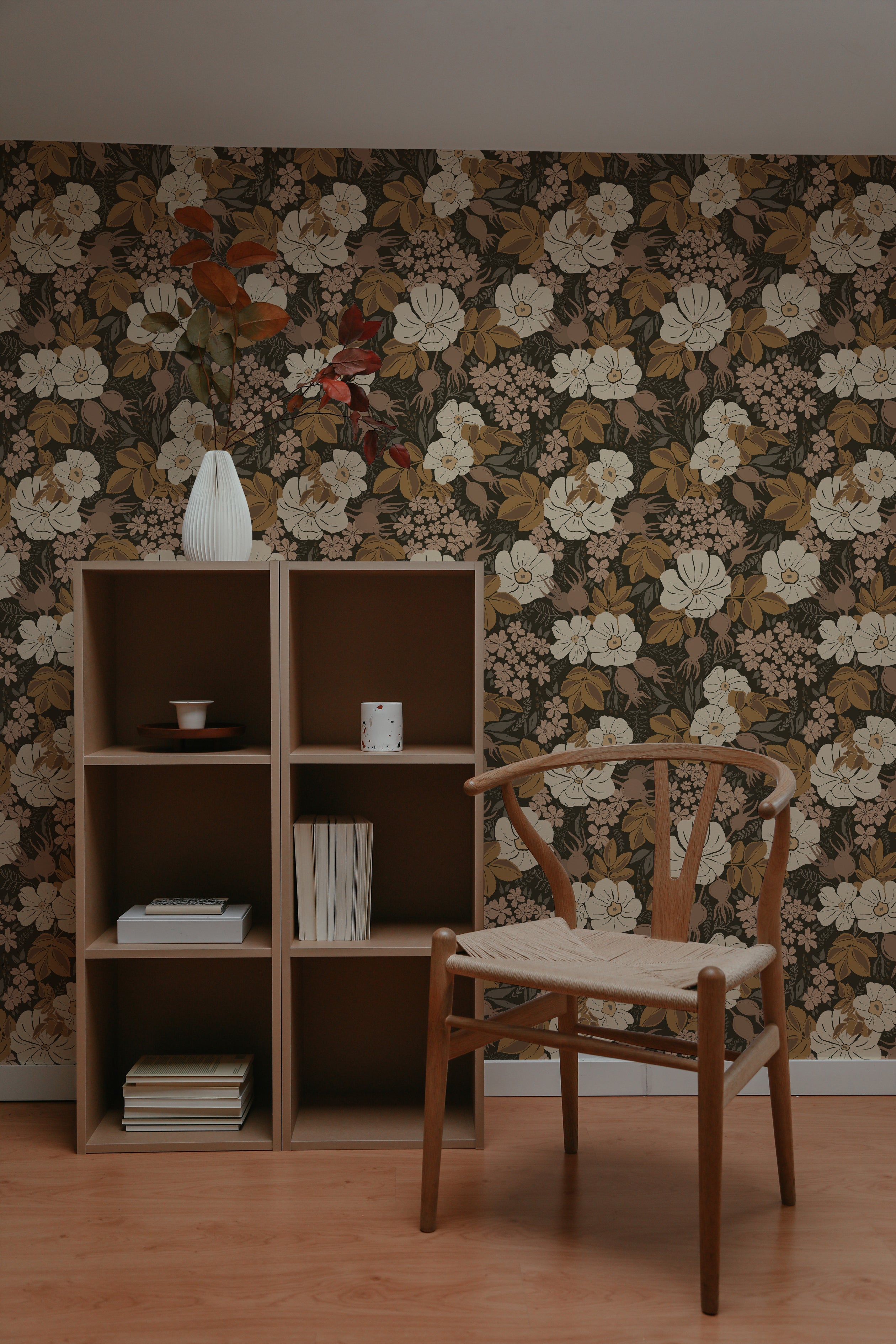 A stylish study corner with a wooden chair and a simple desk under a modern lamp. The Rosehip Wallpaper in the background features large white flowers and dense foliage, creating a serene and inspiring workspace.
