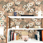 A home office area with a modern white desk, accessorized with books and a small potted plant, against the backdrop of Forest Strawberries Wallpaper. This wallpaper, featuring a lush pattern of white flowers and strawberries, brings a fresh and vibrant touch to the study space.