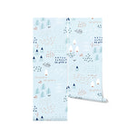 A roll of "Nordic Adventure Wallpaper" showcasing a playful and abstract pattern of trees, mountains, and scattered elements in cool tones of blue, white, and touches of orange. This design is perfect for adding a sense of outdoor adventure to any child's room or play area.