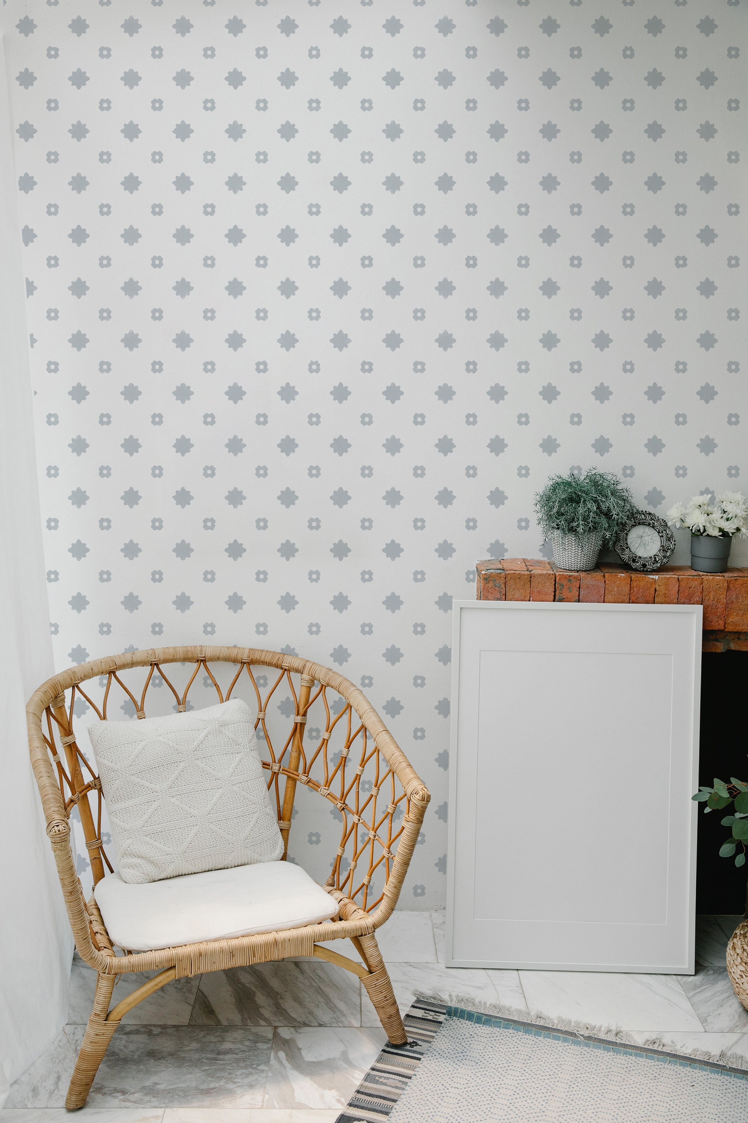 A detail of Friedrich Wallpaper showing the clean and minimalist design of light grey floral motifs scattered uniformly on a white background, perfect for creating a serene and uncluttered space.