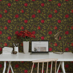 A modern workspace featuring a white desk with a vase of red flowers, complemented by the Vintage Pomegranate Wallpaper in the background. The rich colors of the pomegranates and leaves bring a vibrant and organic feel to the room.