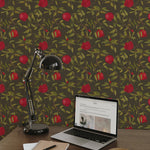 An office setup with a sleek, black desk lamp illuminating a laptop on a wooden desk, set against a background of Vintage Pomegranate Wallpaper. The wallpaper’s vivid red pomegranates and green leaves on a dark backdrop add a touch of nature-inspired elegance to the workspace.