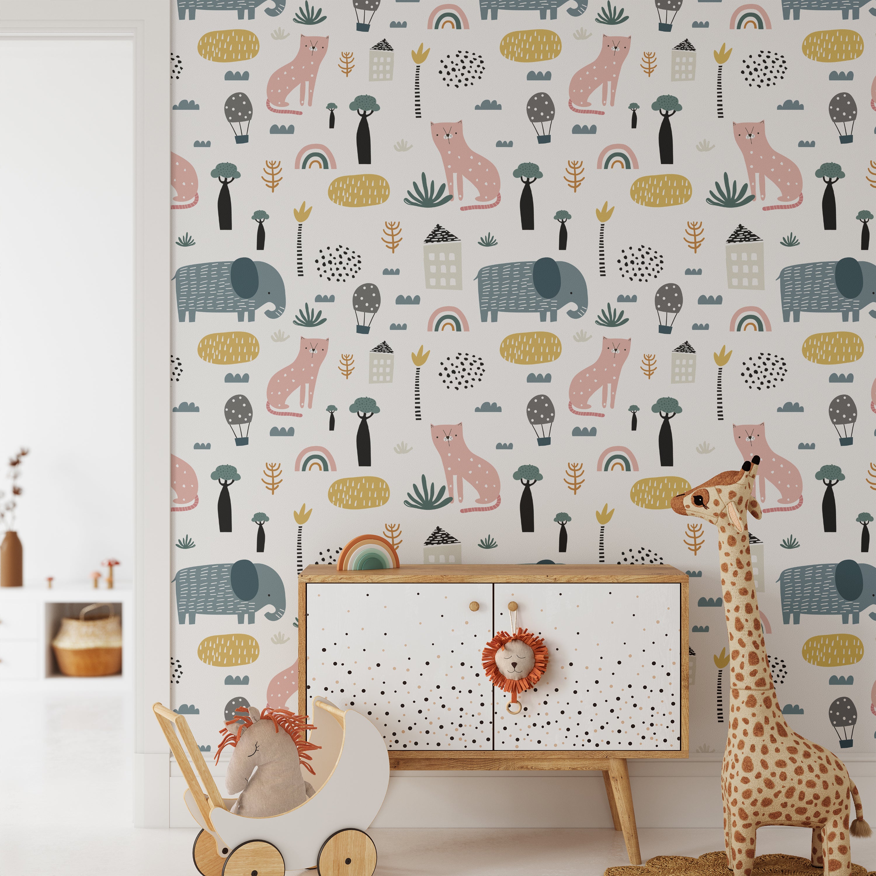 A playful children's room featuring Fox and Elephant Wallpaper, adorned with whimsical patterns of pink foxes, blue elephants, rainbows, and trees on a light background. The room includes a wooden toy horse and a cabinet decorated with a lion toy, creating a vibrant and imaginative space.