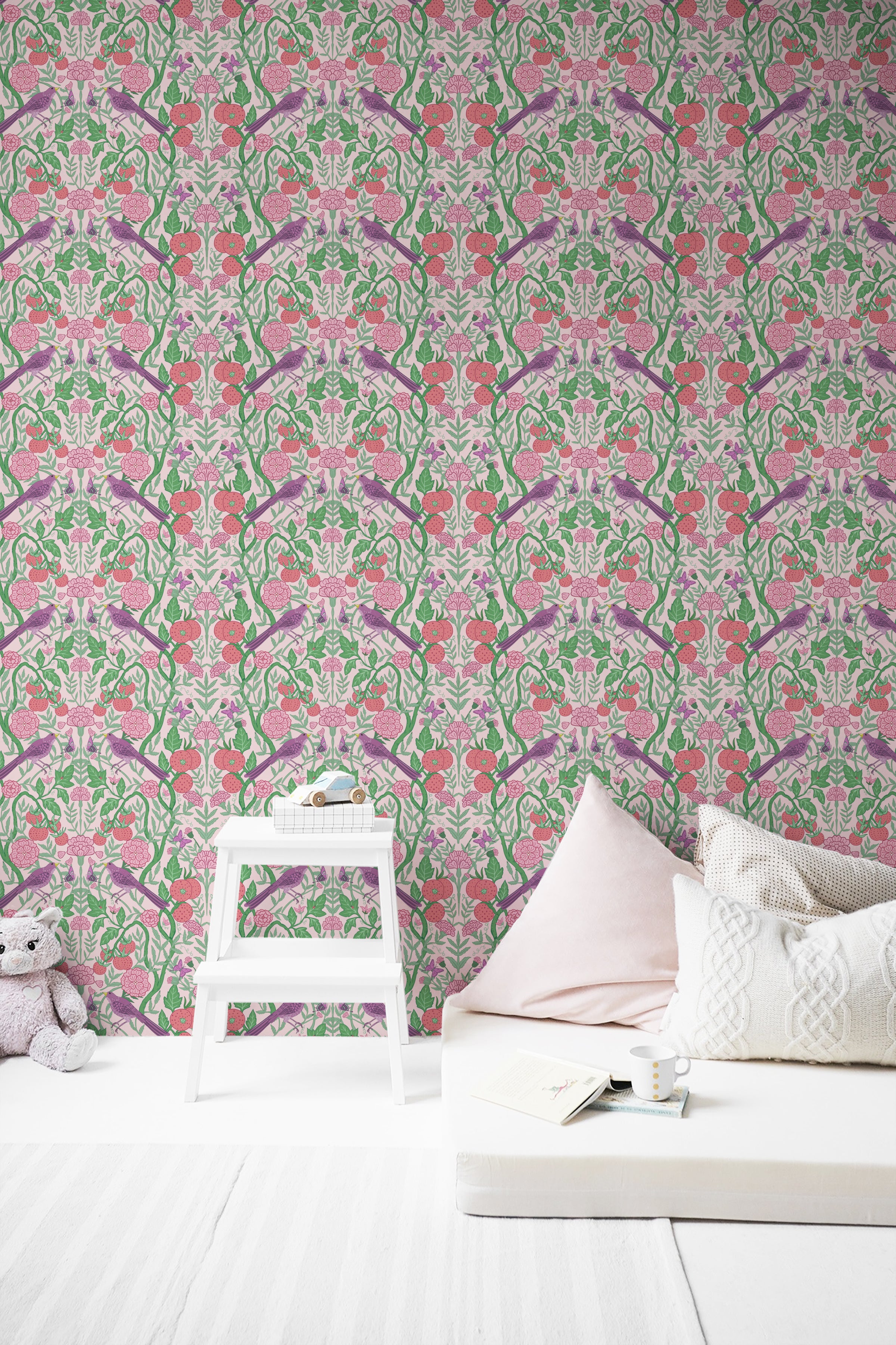 A stylish reading nook with a low, modern white bed covered with a cushion and throw pillows, positioned against a detailed floral and bird-themed wallpaper. A small white step ladder used as a side table holds a book and a coffee cup, enhancing the room's calm and relaxing atmosphere."