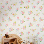 Child-friendly corner with the Rōma Hito Wallpaper displaying playful pink and blue flowers. The decor includes a plush teddy bear, pine cones, and a soft blanket, creating a warm and welcoming play area for children