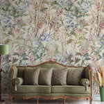 A luxurious living room setting with the "Ancient Florals Wallpaper" enveloping the space in a tapestry of soft, vintage floral designs. A classic green velvet couch sits against the wallpaper, perfectly complemented by the naturalistic elements of the decor.