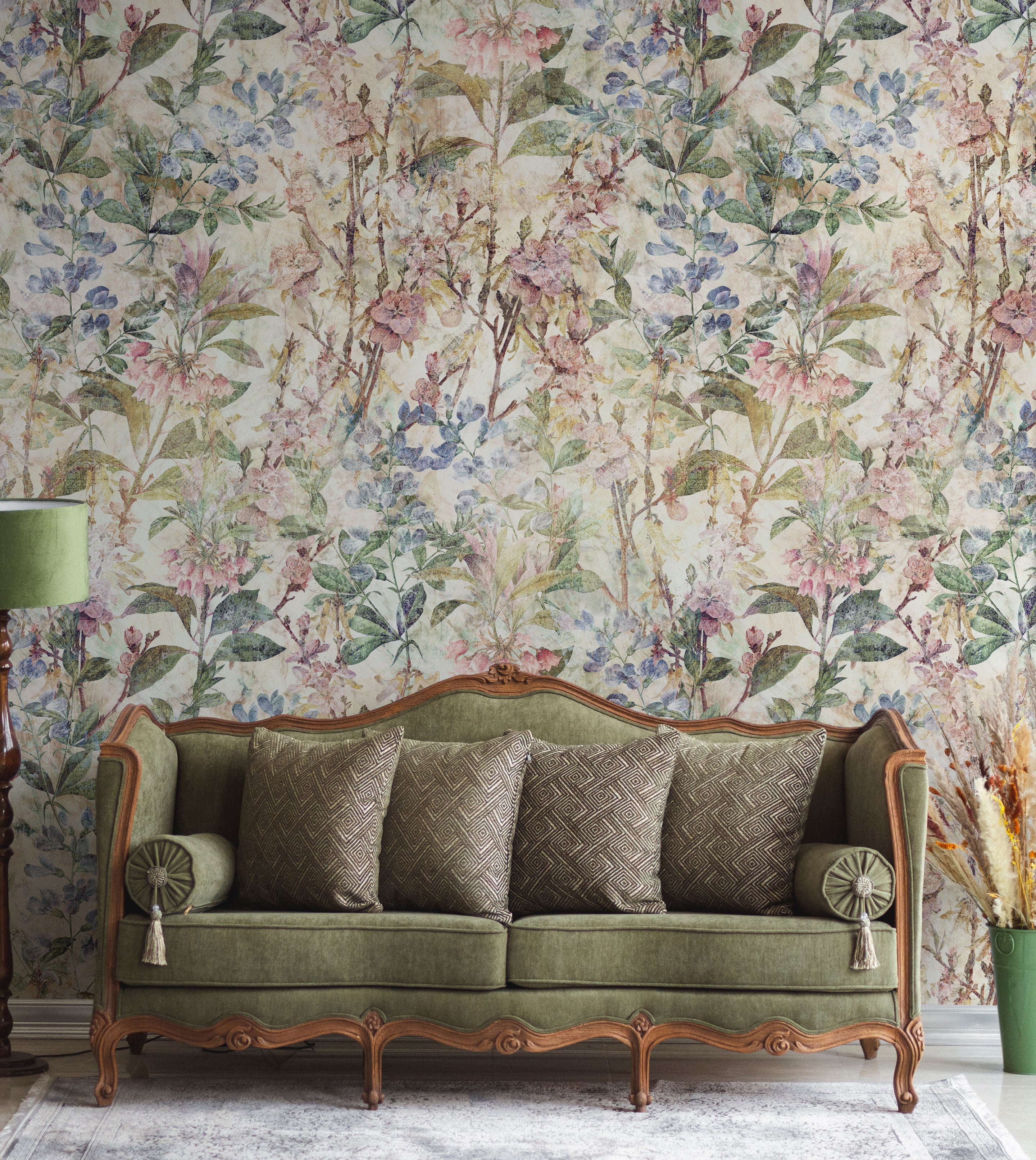 A luxurious living room setting with the "Ancient Florals Wallpaper" enveloping the space in a tapestry of soft, vintage floral designs. A classic green velvet couch sits against the wallpaper, perfectly complemented by the naturalistic elements of the decor.