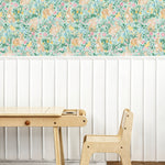 Close-up of a vibrant children's wallpaper depicting a lush, floral scene with rabbits and various spring flowers in soft pastel colors. Positioned beside a simple wooden desk and chair set, enhancing a calm study environment.