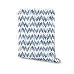 A rolled-up wallpaper sample revealing the Moroccan Tile pattern, which consists of white and navy watercolor zigzag shapes, giving a sophisticated and contemporary feel to the design.