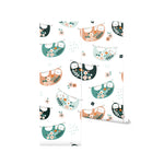 A roll of the Sloths Nursery Wallpaper. The design showcases cute sloths in green, peach, and black, adorned with flowers, hanging from branches on a white background, creating a fun and whimsical atmosphere.