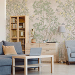 Image of a cozy home office area with chinoiserie wallpaper featuring a delicate tree and bird design that adds a peaceful and artistic backdrop to the room furnished with a light wood desk, shelving, and blue textiles
