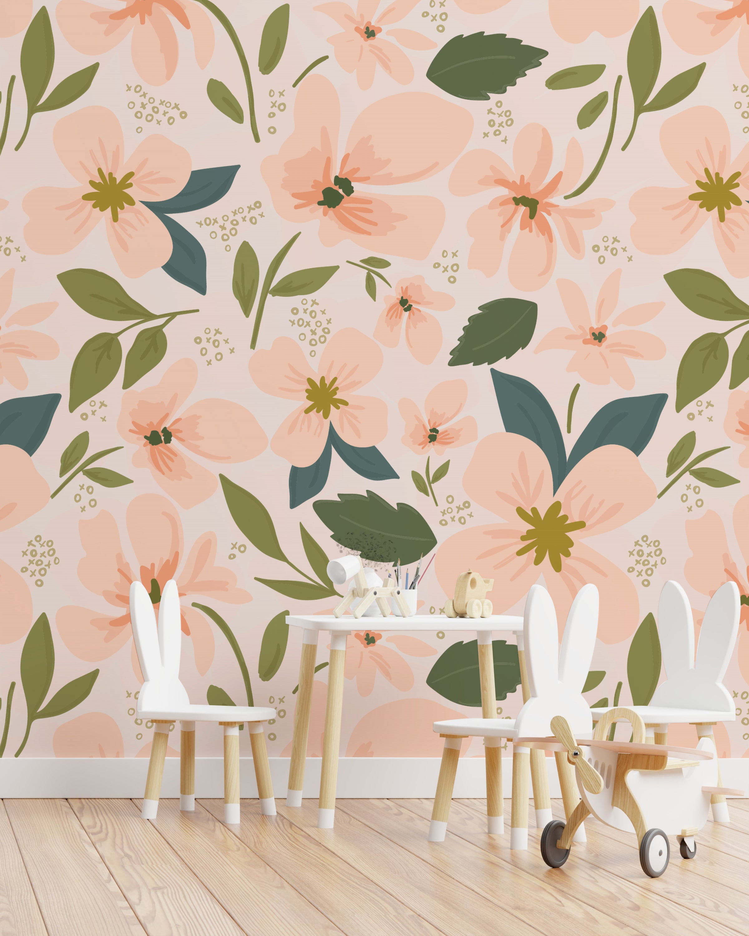Children's play area with small white chairs and toys in front of a wall covered in soft peach floral wallpaper