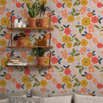 A wall covered in wallpaper with a dense floral design of roses and small flowers, complemented by wooden shelves with potted plants and decorative items