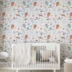 A cozy corner of a nursery room decorated with space-themed wallpaper displaying cute rockets and celestial bodies, with a white crib, grey bedding, and wooden letters on the floor