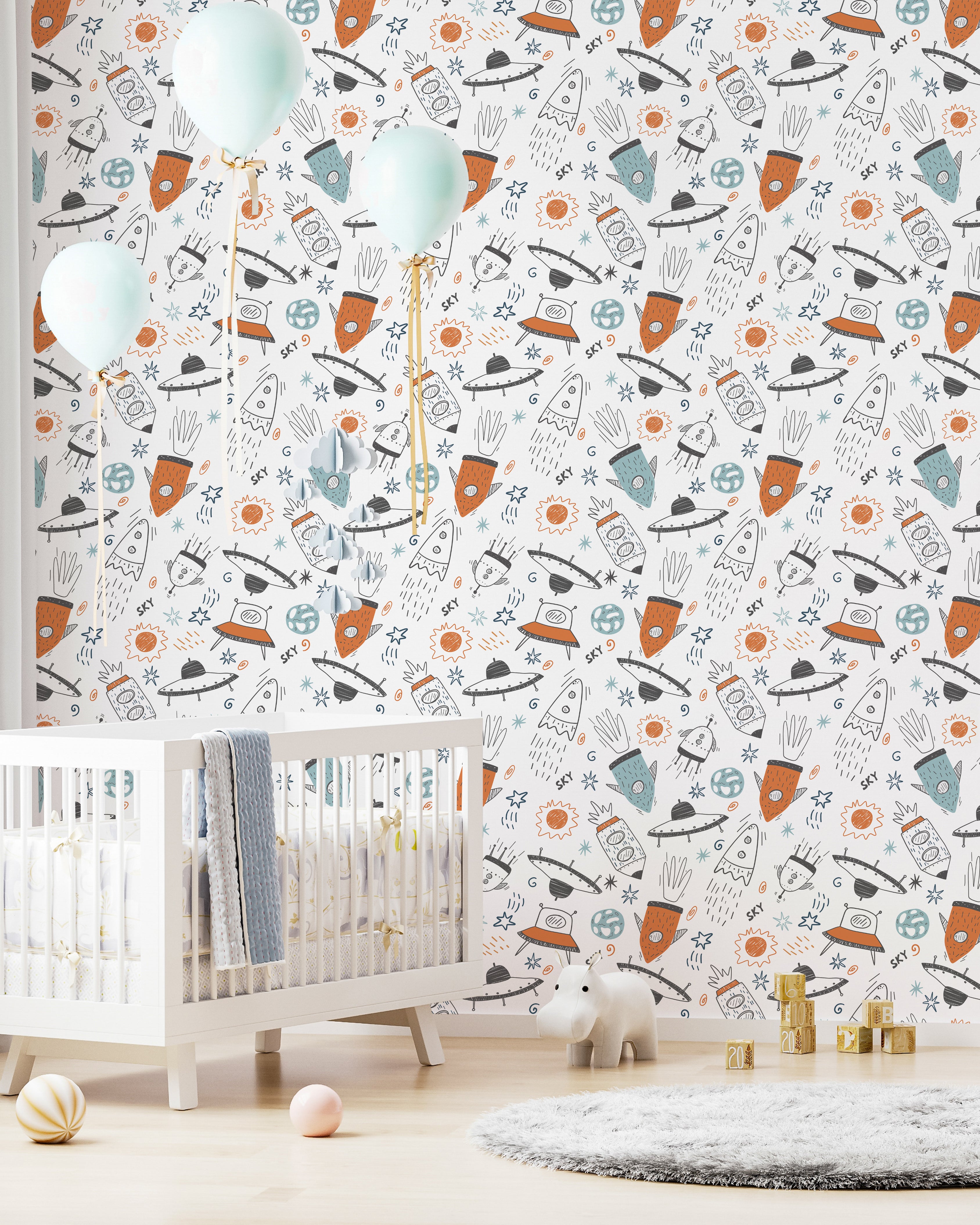 A nursery room with walls covered in space-themed wallpaper showcasing a whimsical array of rockets, planets, and stars, accompanied by light blue balloons, a white crib, and a grey carpet