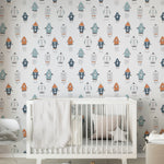 Corner of a nursery with space-themed wallpaper filled with colorful rockets, complementing a white crib and neutral room decor