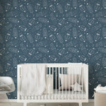 A nursery with walls adorned by 'Cosmic Doodles' wallpaper, complemented by a white crib, star-shaped pillows, and soft, inviting textures.