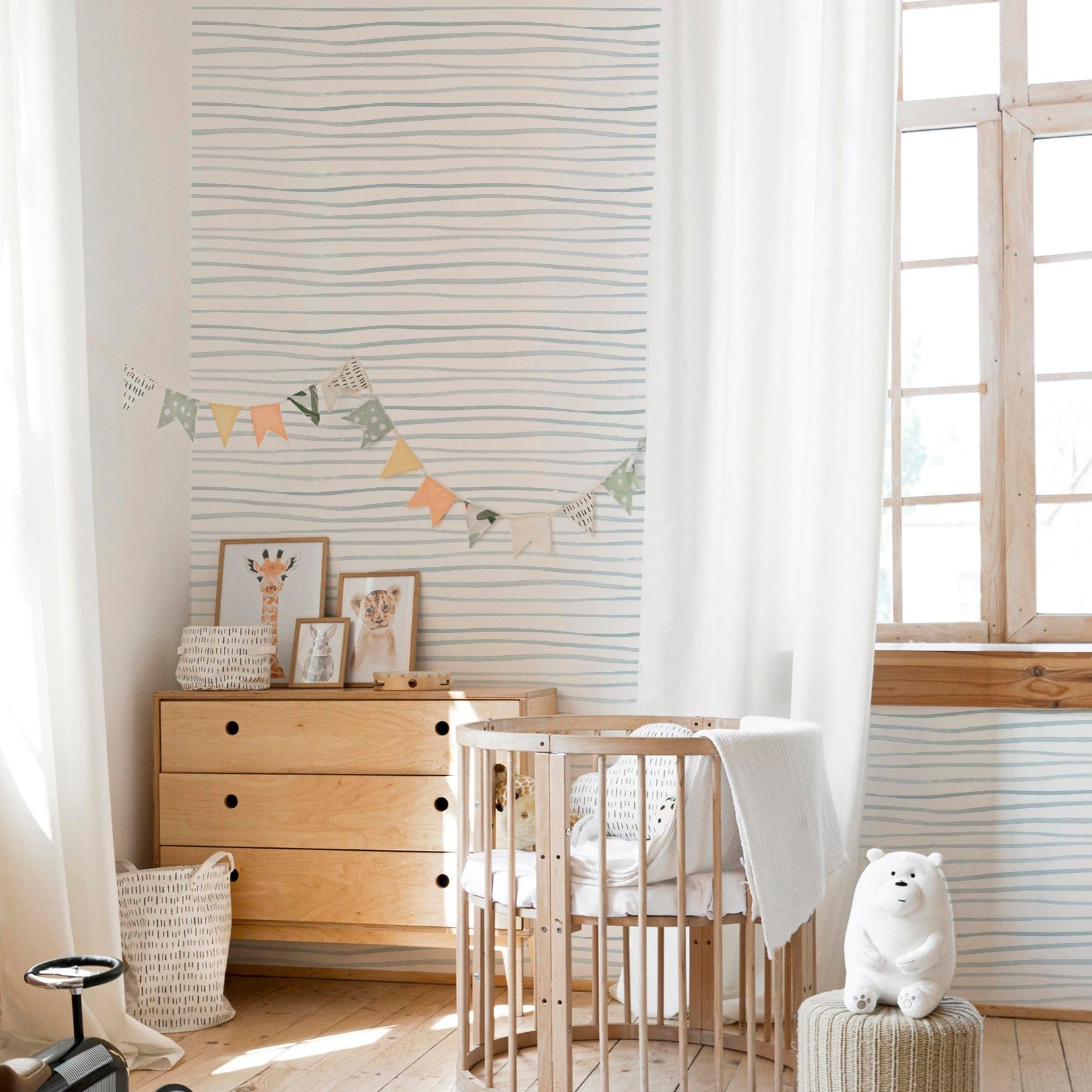 A cozy nursery with wooden furniture and soft lighting, decorated with wallpaper featuring minimalistic blue brush stroke lines, creating a serene and inviting atmosphere.