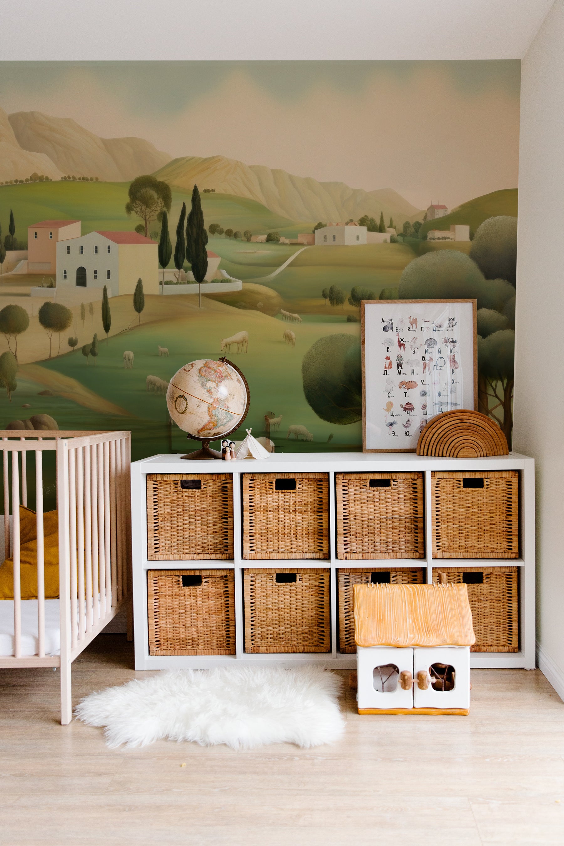 Nursery room showcasing a pastoral landscape mural with a crib, wicker storage baskets, and a plush white rug.