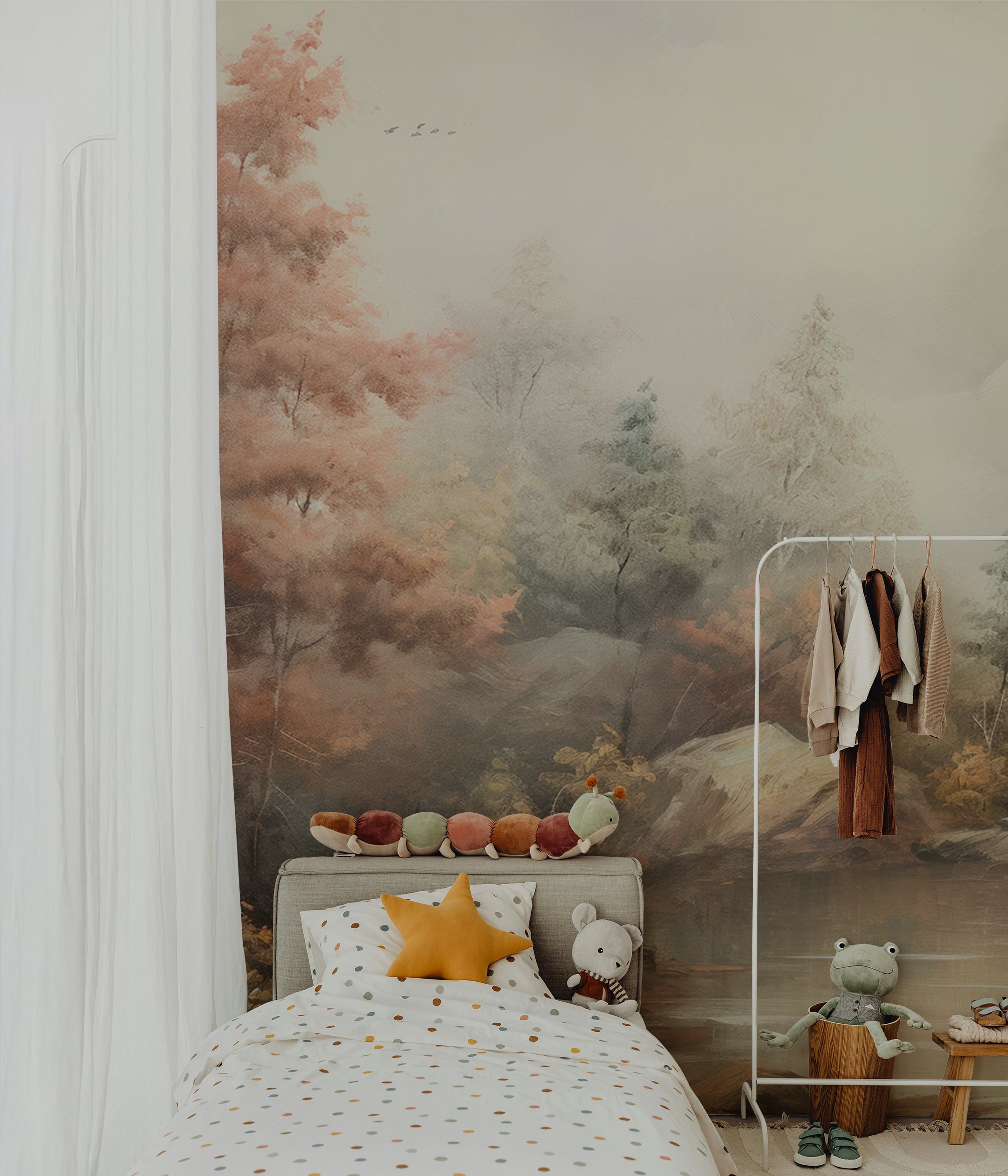 Cozy kids' room featuring the Fall Lake Mural as a backdrop. The mural depicts a peaceful lake and autumnal forest scene, with a bed, plush toys, and clothing rack complementing the serene, natural ambiance.