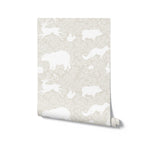 A roll of warm beige wallpaper showcasing a pattern of white woodland animals like bears, foxes, and rabbits, creating a charming and nature-inspired design suitable for various interior settings