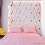 A cozy bedroom setting with Little Mermaids Wallpaper providing a lively and imaginative backdrop. The bed is dressed in pink linens, complementing the colorful mermaids and enhancing the room’s playful and magical atmosphere.