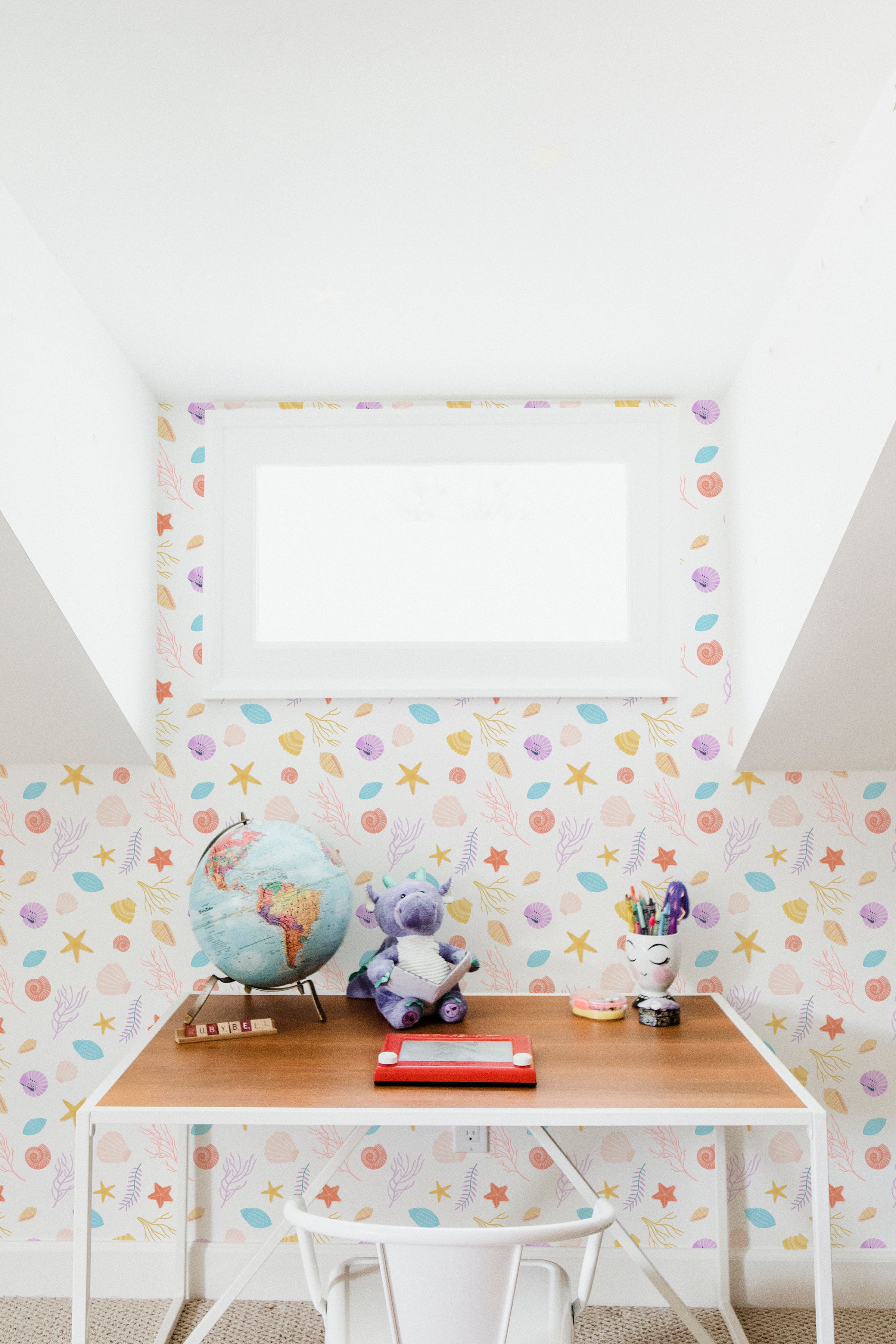 A playful children's workspace with Colourful Sea Wallpaper, featuring a vibrant pattern of various sea shells, starfish, and coral in pastel colors, providing a lively and educational backdrop