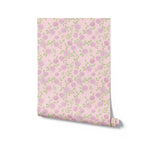 Roll of floral wallpaper with purple flowers on a pink background