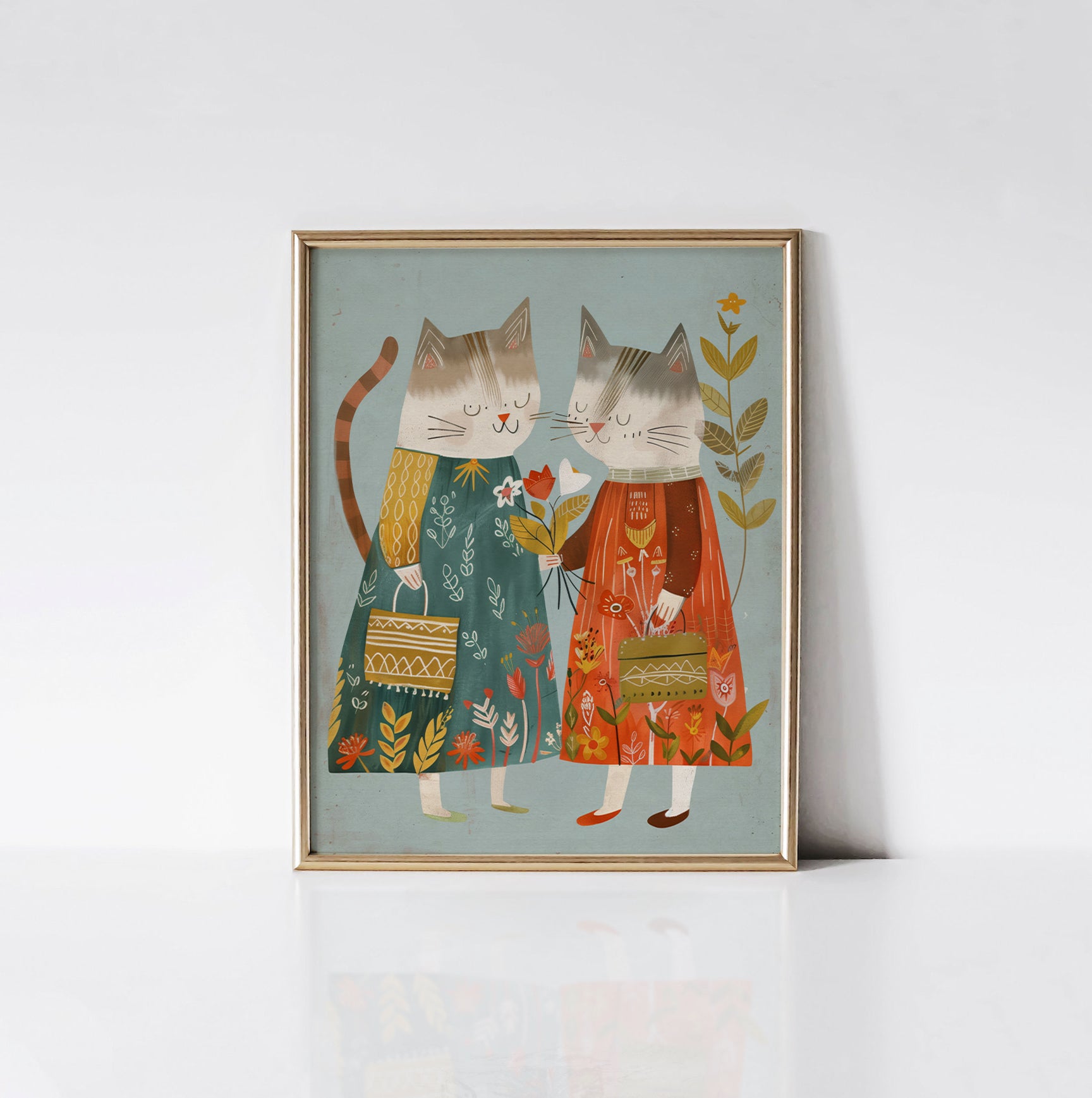 Art print of two cats in colorful floral-themed dresses, framed in a gold frame, adding a whimsical touch to a child's room decor