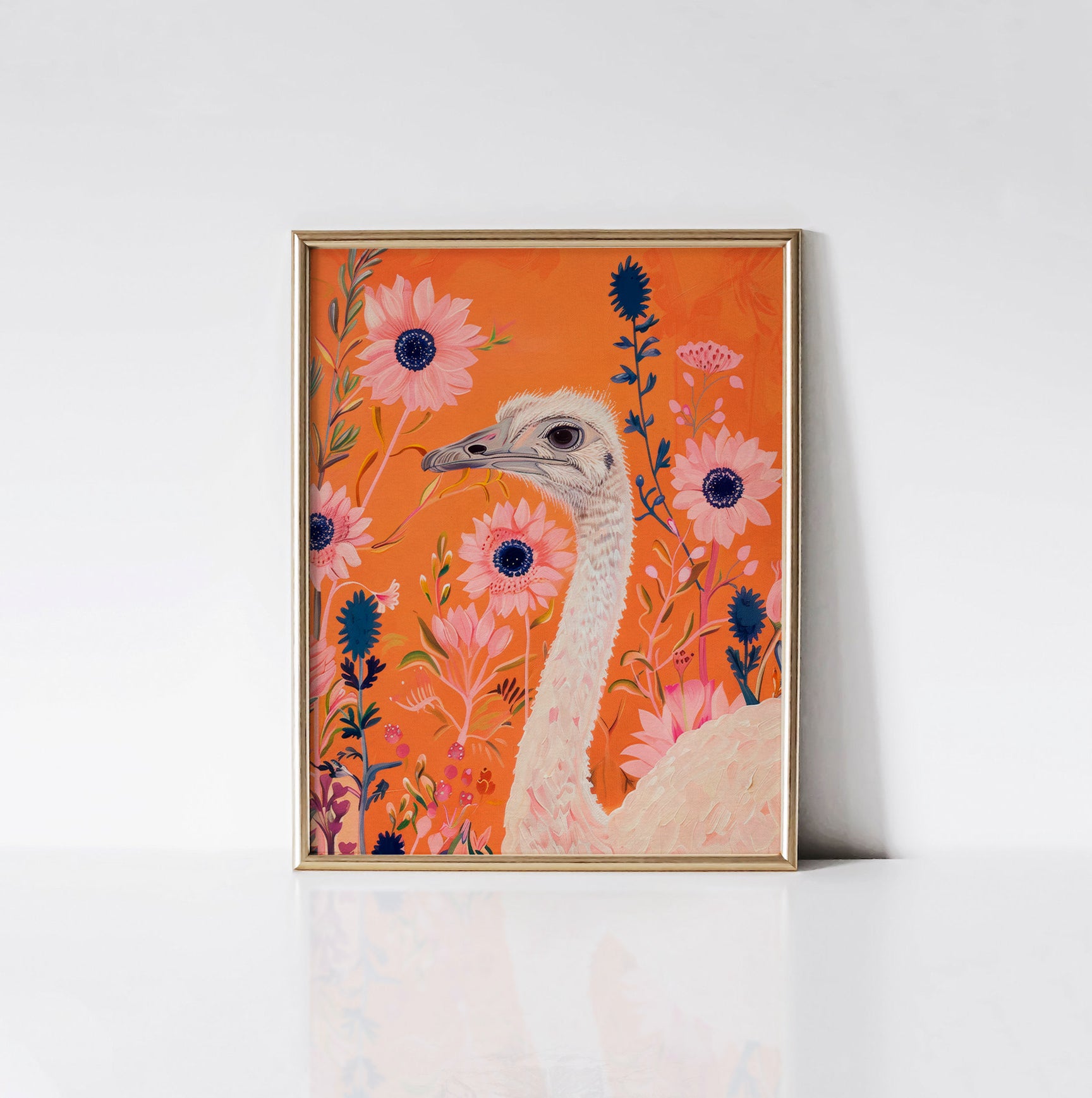 Ostrich in Bloom Art Print framed in an elegant gold frame, depicting a graceful ostrich surrounded by lively pink and blue flowers against a bold orange background.