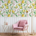 Contemporary living space accented with Citrus Blossom Wallpaper, which infuses the room with a burst of nature-inspired beauty. The wallpaper features yellow lemons and pink blossoms, complementing the modern pink armchair and golden decor elements, adding sophistication and warmth