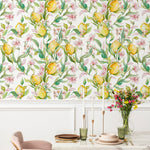 Elegant dining area enhanced by Citrus Blossom Wallpaper, featuring lush yellow lemons and pink blossoms on a vibrant green vine pattern. The fresh and lively wallpaper sets a charming backdrop for the chic marble table and plush pink chairs, creating an inviting space for dining